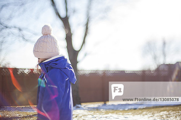 Seitenansicht eines Mädchens mit Strickmütze  das an einem sonnigen Wintertag im Hof steht