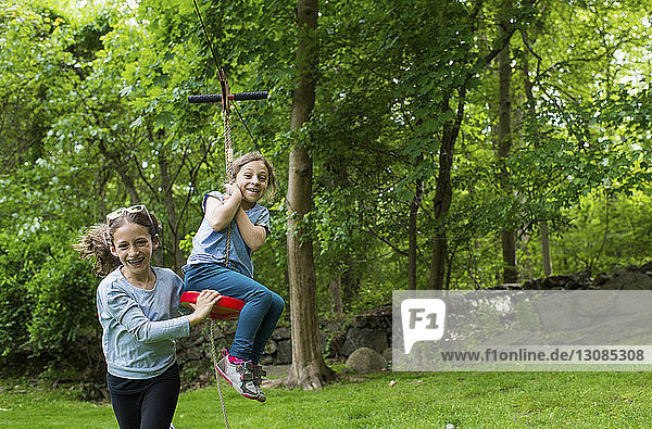 Happy sisters playing with zip line at park