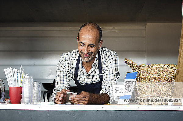 Verkäufer benutzt Smartphone  während er im Speisewagen steht