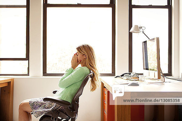 Tired businesswoman sitting at office desk by window