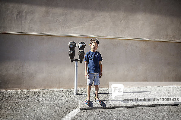 Boy standing against binoculars on road against wall