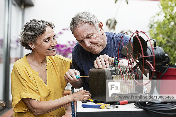 Älteres Ehepaar repariert altmodisches Radio auf dem Hof