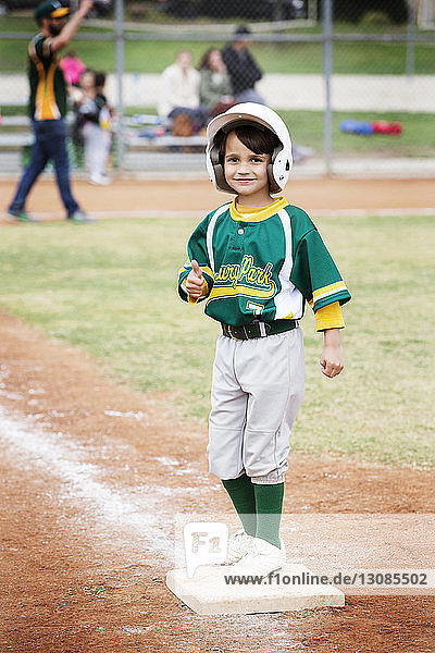 Portrait of smiling boy showing thumbs up on baseball field