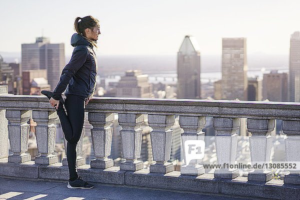 Young woman stretching outdoors looking at city