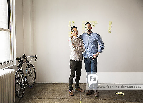 Portrait of business colleagues standing against white wall in creative office
