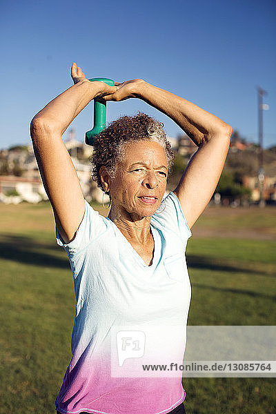 Woman exercising in park against clear blue sky