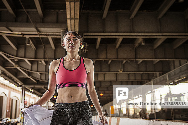Selbstbewusste Frau mit Sport-BH unter der Brücke stehend