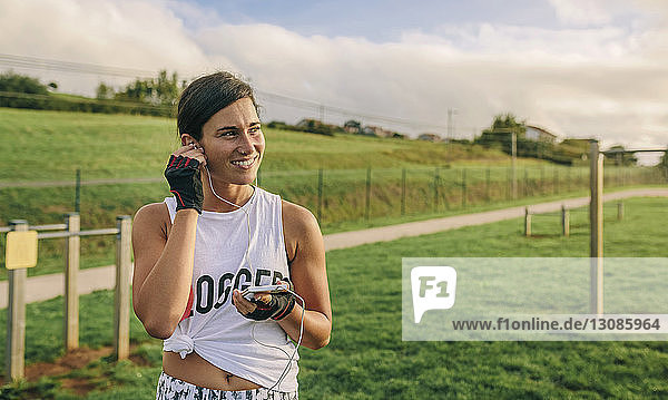 Happy woman listening music while exercising at park
