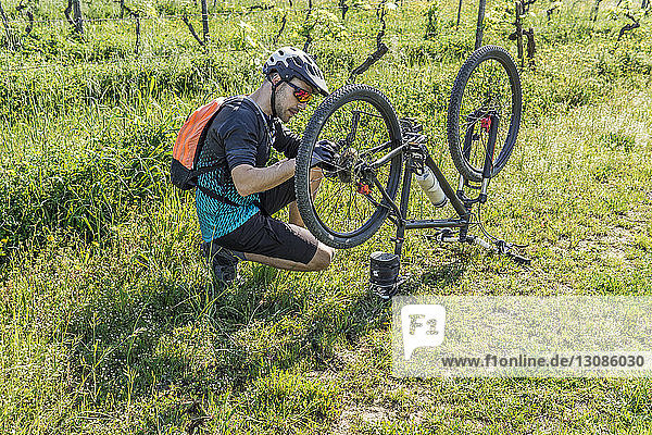 Full length of young man repairing mountain bike on field