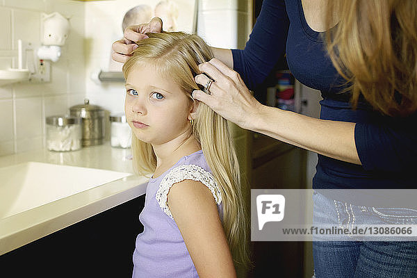 Mittelteil einer Frau  die die Haare ihrer Tochter macht