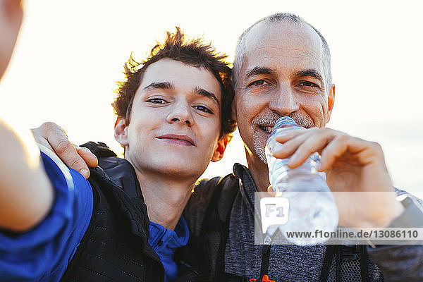 Close-up portrait of happy father and son against sky