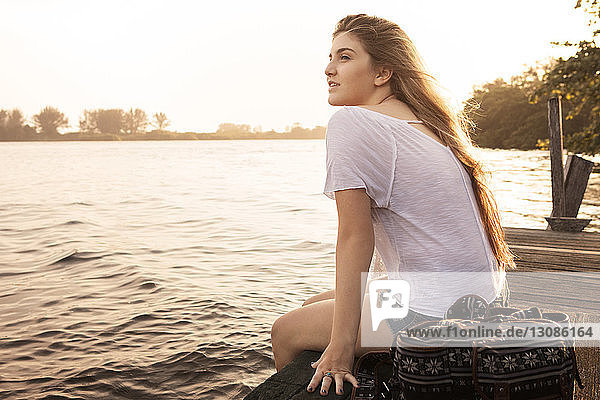 Teenage girl relaxing on pier at sunset