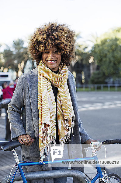 Porträt einer glücklichen Frau mit Fahrrad im Park stehend