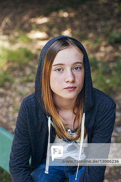 Porträt einer selbstbewussten Teenagerin im Park sitzend
