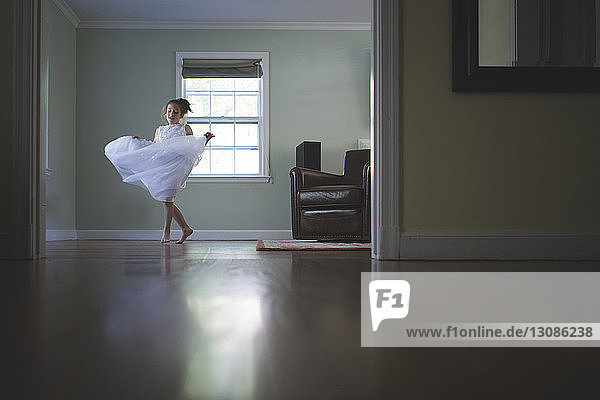Mädchen in voller Länge in weißem Kleid tanzt zu Hause im Zimmer
