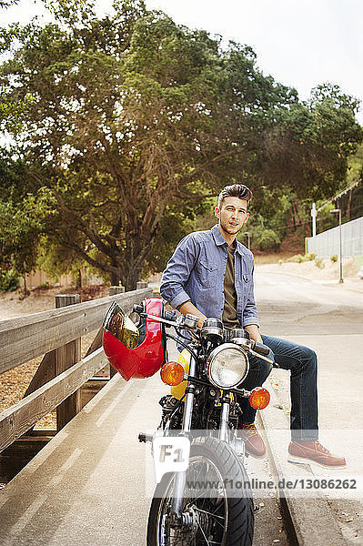 Porträt eines gutaussehenden Mannes auf einem Motorrad sitzend