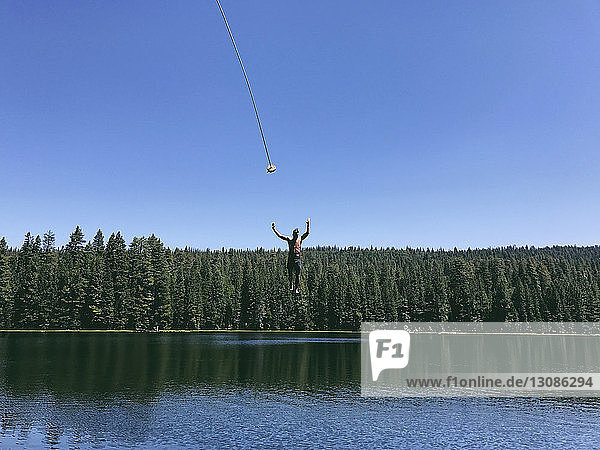 Mann ohne Hemd springt im Rucker-See bei strahlend blauem Himmel am sonnigen Tag