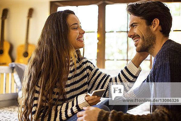 Glückliches Paar redet  während es zu Hause auf einem Fensterplatz in einer Nische sitzt