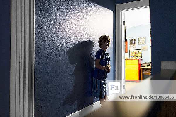 Porträt eines Jungen  der zu Hause an einer blauen Wand steht