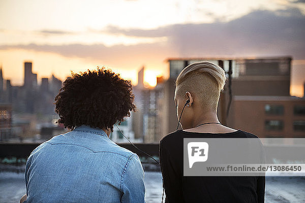 Ein Paar hört bei Sonnenuntergang auf dem Dach Musik