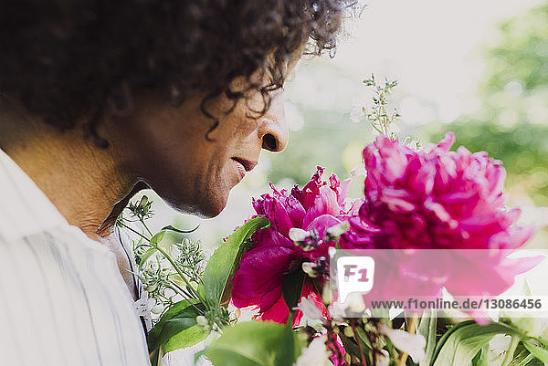 Cropped image of woman smelling freshly harvested flowers in garden