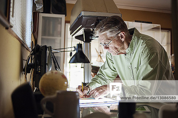 Älterer Mann arbeitet zu Hause am Grafiktablett
