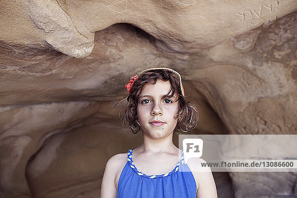 Portrait of girl standing against rock in cave