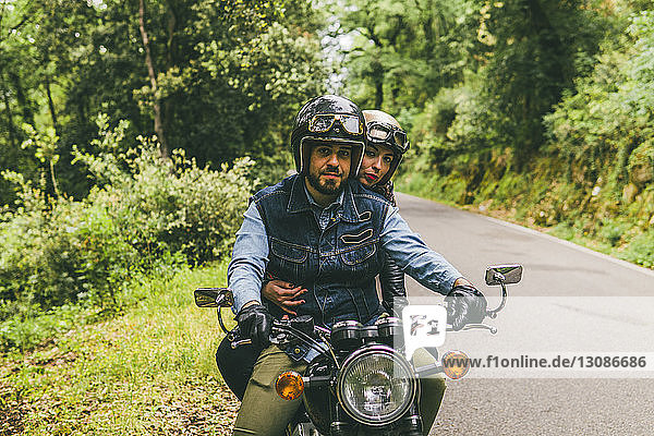 Porträt eines Motorrad fahrenden Ehepaares auf einer Straße im Wald