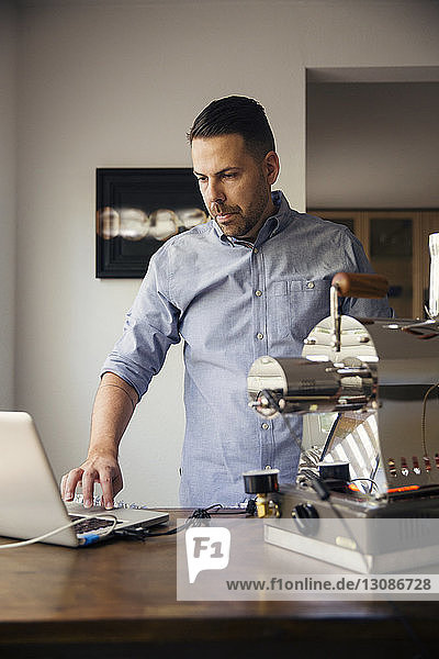 Mann benutzt Laptop und Kaffeeröster im Café