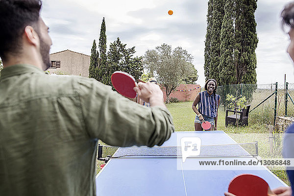 Multi-ethnische Freunde spielen Tischtennis im Hof