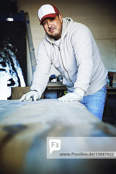 Porträt eines lächelnden Handwerkers  der Holz in der Werkstatt bearbeitet