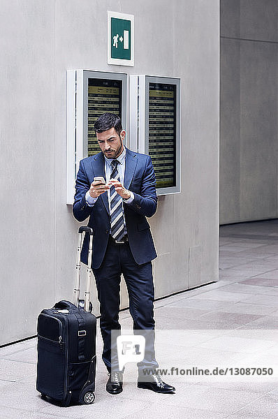 Geschäftsmann in voller Länge mit Smartphone in der U-Bahn-Station