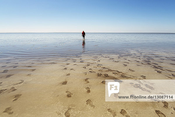 Mid distance of man walking on beach against blue sky
