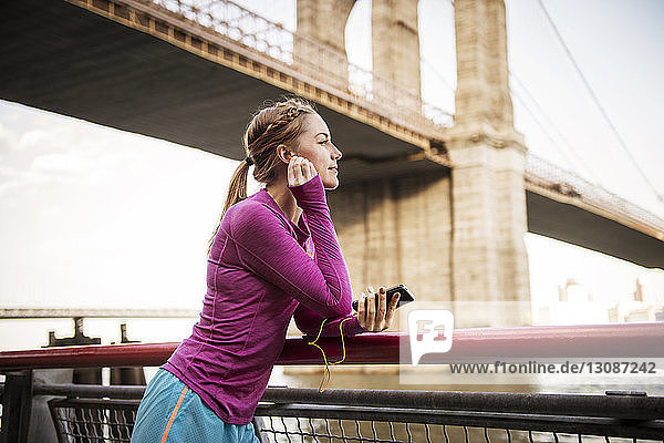 Frau hört Musik  während sie an der Brooklyn-Brücke steht