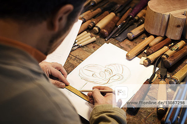 Männlicher Handwerker beim Zeichnen auf Papier in der Werkstatt