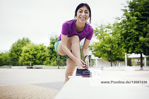 Porträt einer glücklichen sportlichen Frau mit Schuhen auf einem Fußweg