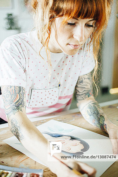 Künstlerin malt stehend am Tisch im Atelier