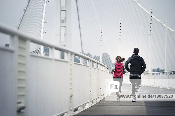 Rückansicht von Athleten die auf der Bay Bridge gegen den Himmel laufen