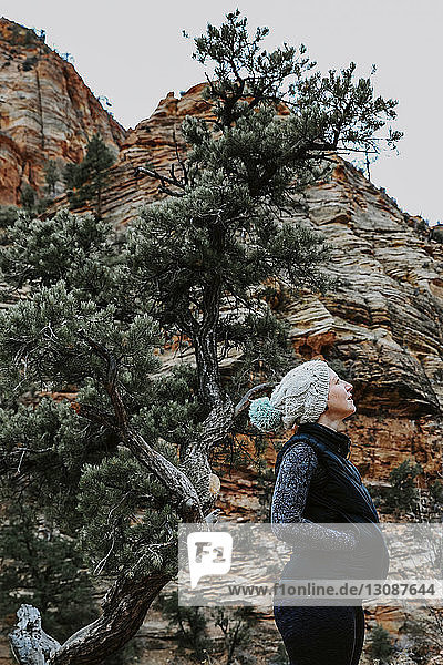 Seitenansicht einer Frau in warmer Kleidung  die im Zion-Nationalpark an den Bergen steht