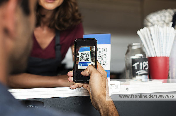 Ausgeschnittenes Bild eines Kunden  der am Imbisswagen per Smartphone bezahlt
