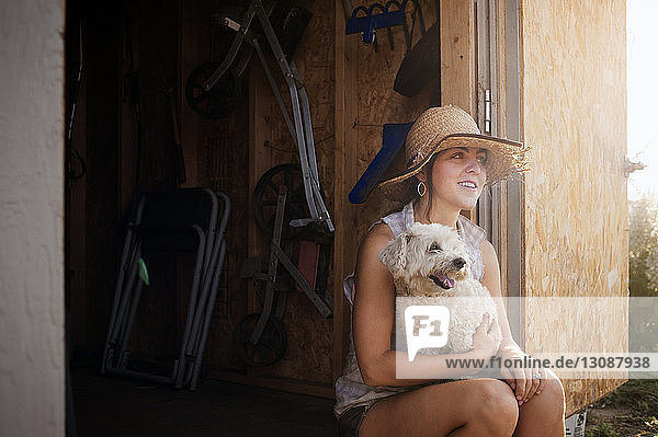 Nachdenkliche Bäuerin sitzt mit Hund in Hütte auf dem Feld