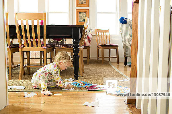 Side view of girl coloring while sitting in living room at home