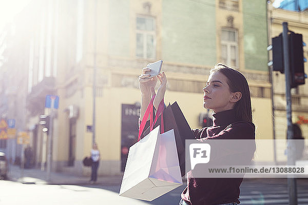 Frau mit Einkaufstaschen fotografiert bei Sonnenschein auf der Straße in der Stadt