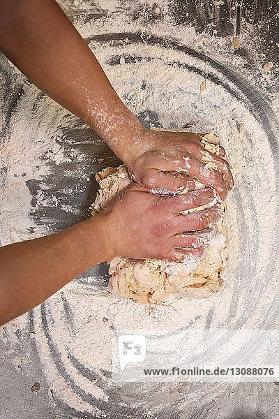 Beschnittenes Bild der Hände des Küchenchefs beim Teigkneten in einer Großküche