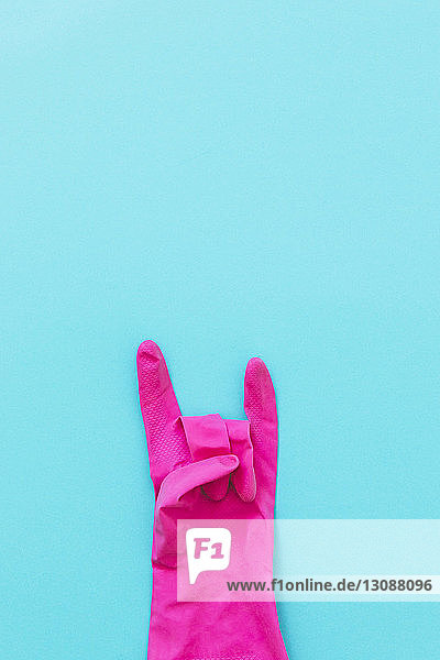 Draufsicht auf rosa Handschuh mit Hornschild auf blauem Hintergrund