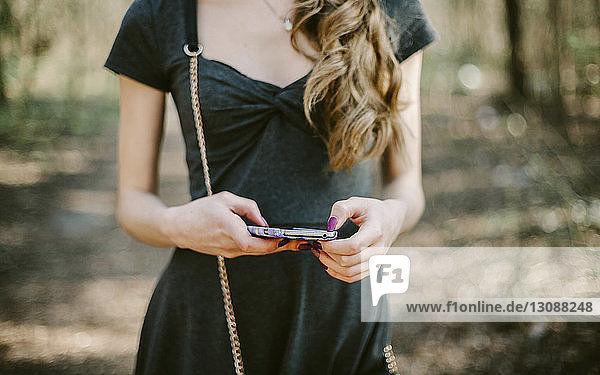 Midsection of young woman using smart phone at park
