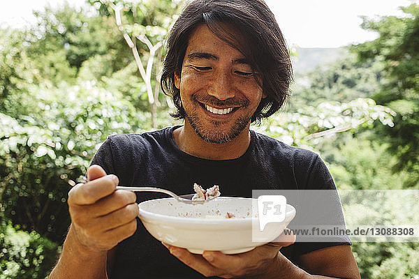 Lächelnder Mann beim Frühstück im Hof
