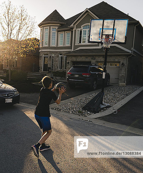 Basketball spielender Junge in voller Länge auf der Straße