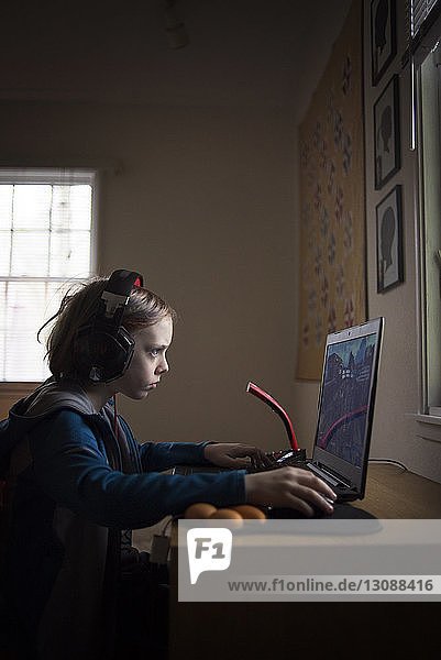 Seitenansicht eines Jungen  der zu Hause am Laptop sitzt