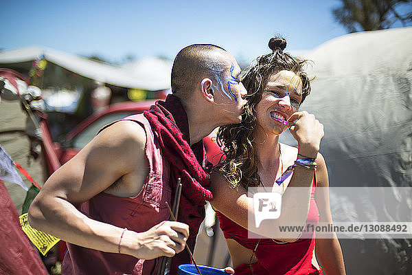 Fröhlicher Mann und Frau mit Gesichtsbemalung genießen während der traditionellen Veranstaltung